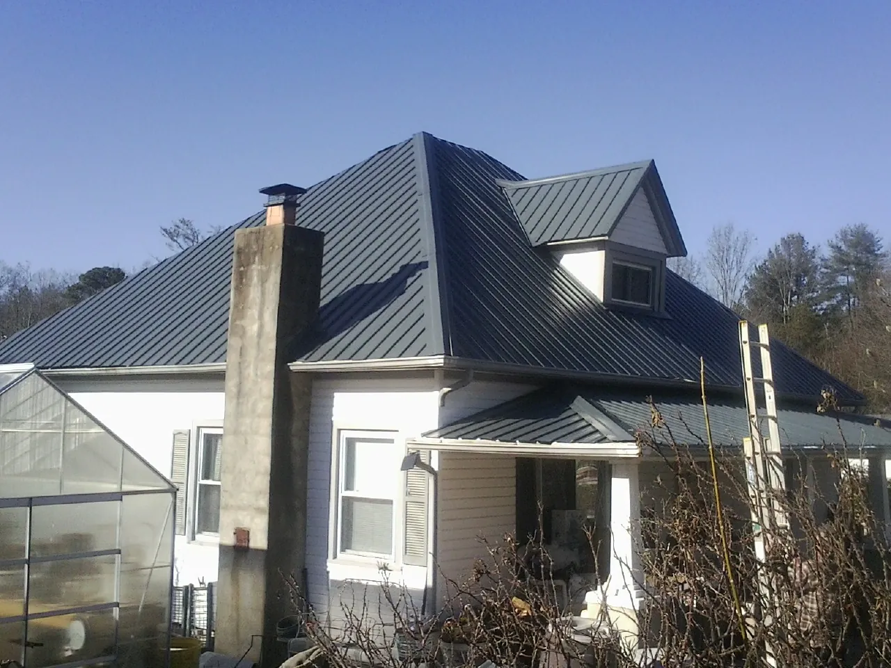 Dark blue standing seam metal roof on a white farmhouse with dormer — Slate & Tile Roof Repair by Roofing Brothers in Dickerson Run