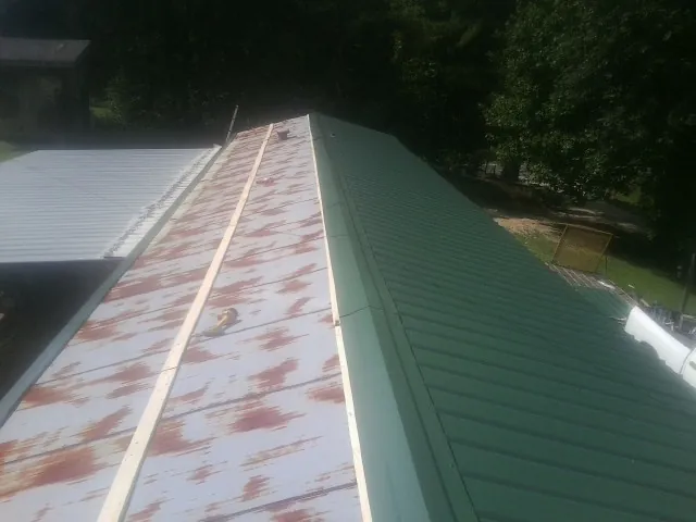 Old rusted panels beside newly installed green metal roofing — Wind Damage Roof Repair by Roofing Brothers in Dickerson Run