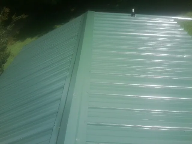New green metal panels meeting at the ridge of a roof — Flat Roof Repair work by our crew in Dickerson Run