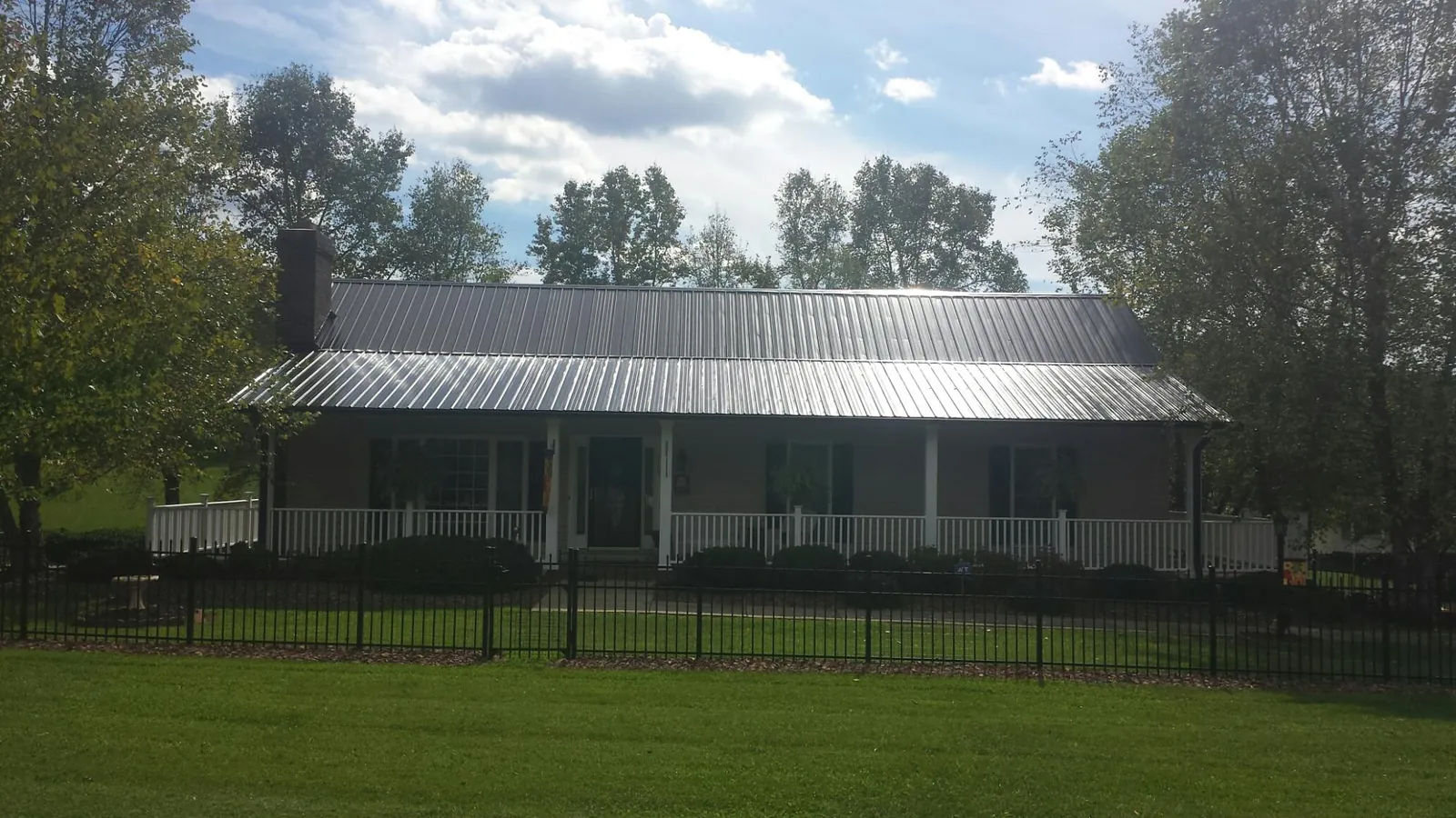 Gray metal roof on a brick ranch with a full width front porch — Gutter Guard Installation work by our crew in Dickerson Run