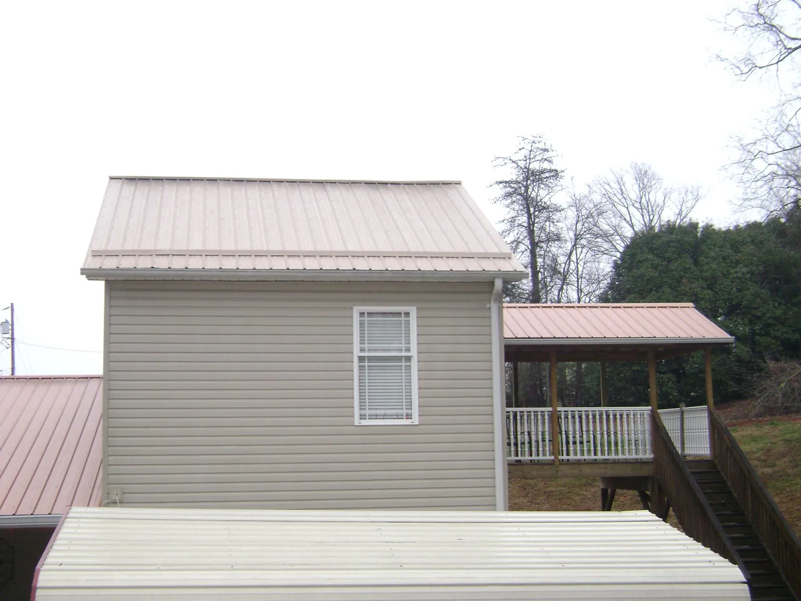 Tan metal roofs on a two story addition and attached porch, from a Roof Replacement job in Dickerson Run