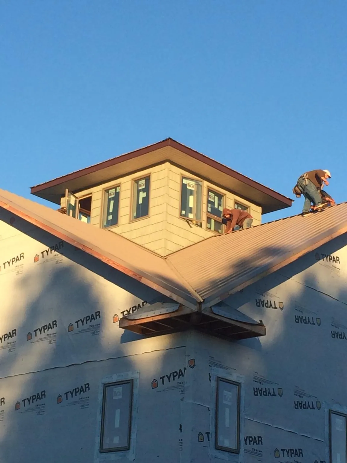 Roofers working around a rooftop cupola on a new metal roof at sunset — Roof Waterproofing in Dickerson Run by Roofing Brothers